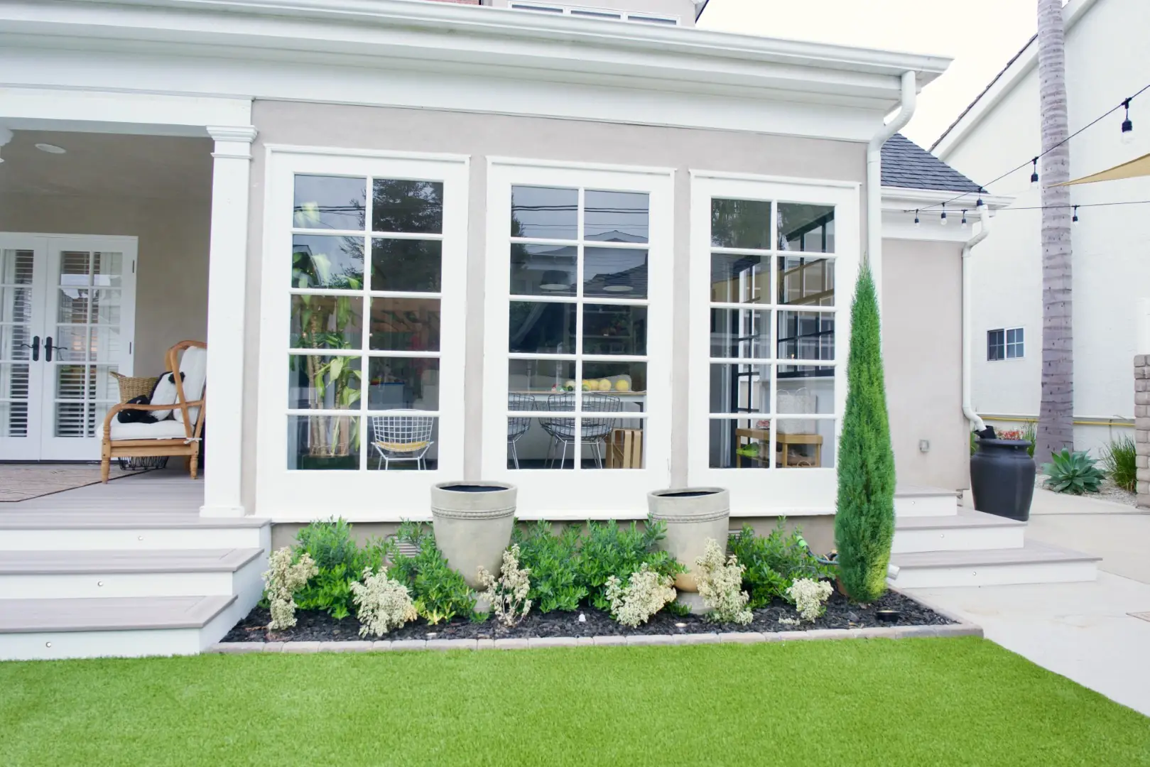 Agnew Project foundation planting with stone urns and flowering shrubs in front of a sunroom and composite steps in Los Angeles
