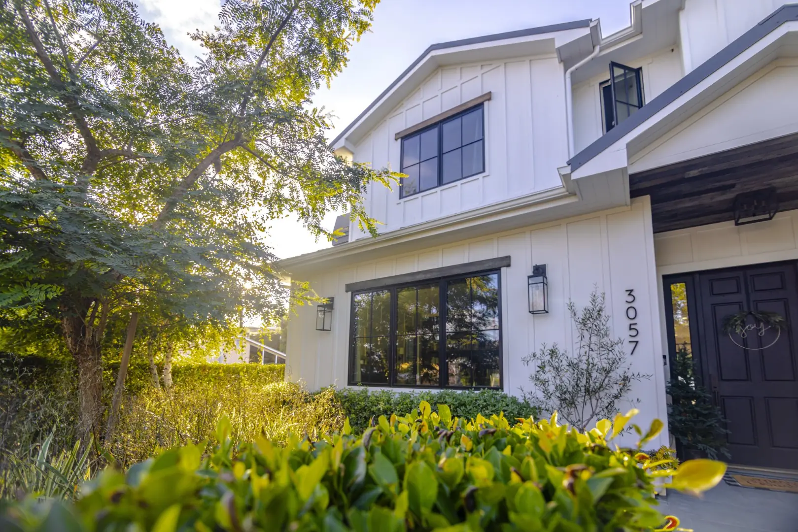 Sheens Project front entry planting with a shade tree and layered shrubs at a board-and-batten farmhouse in Los Angeles