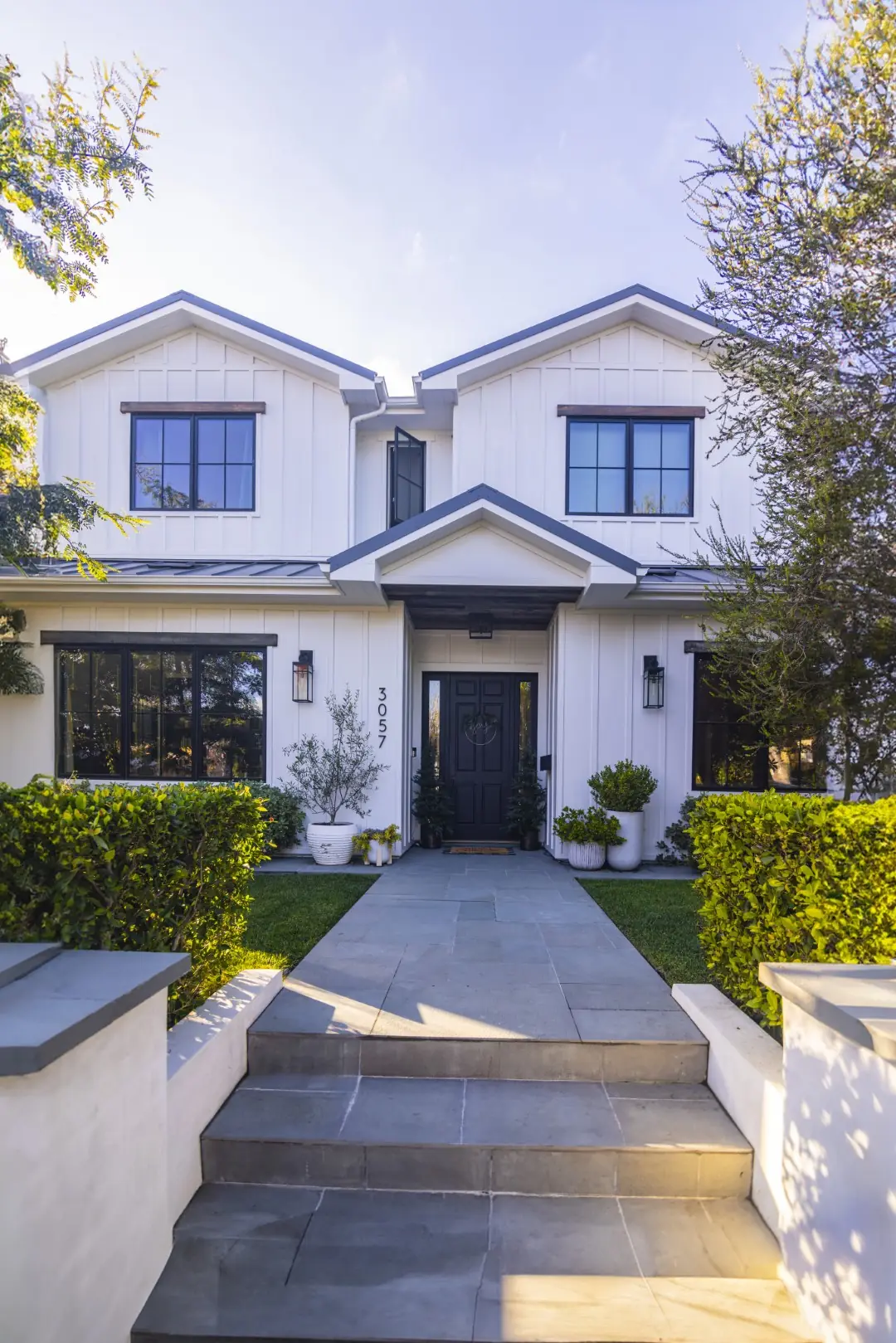 Sheens Project front walkway with stone steps between hedges leading to a white modern farmhouse in Los Angeles