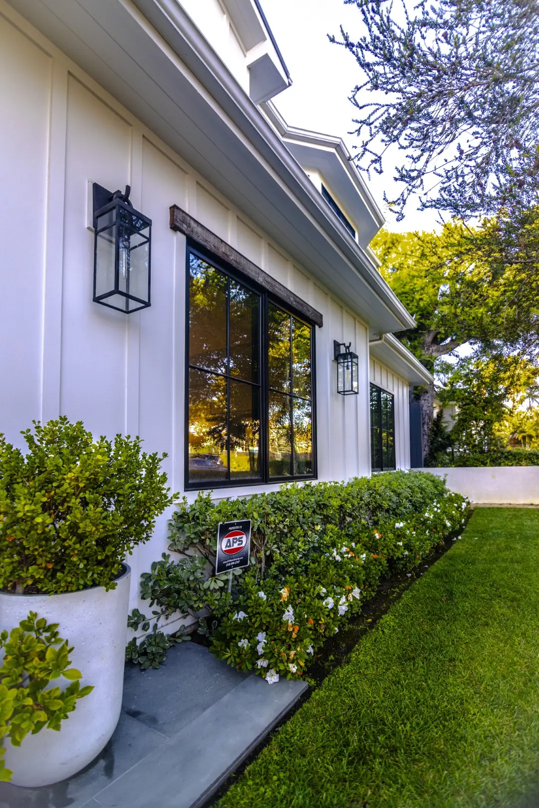 Sheens Project white planters and a flowering hedge along the side of the farmhouse in Los Angeles