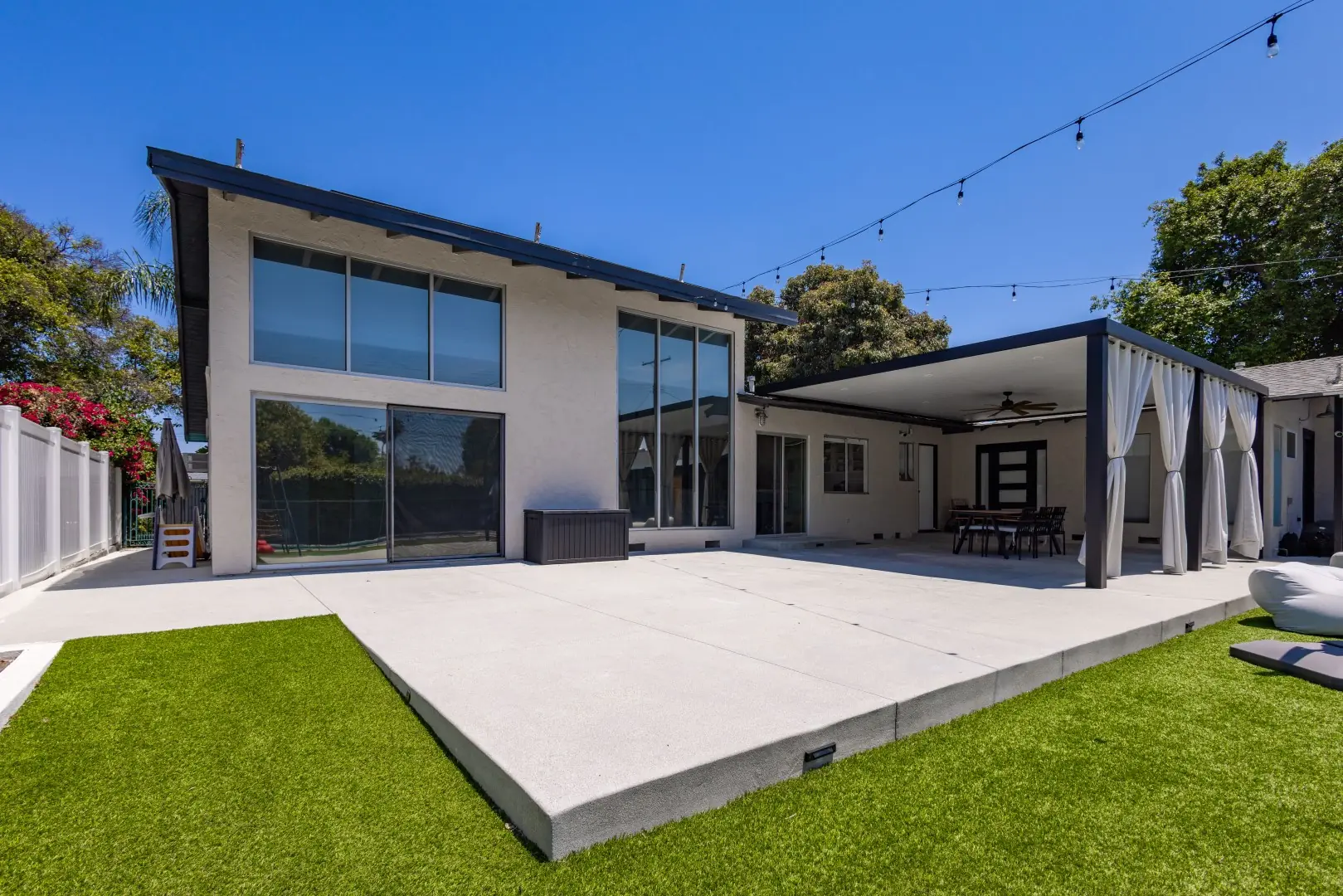 Large concrete patio and curtained pergola at the rear of a modern home in Reseda, Los Angeles
