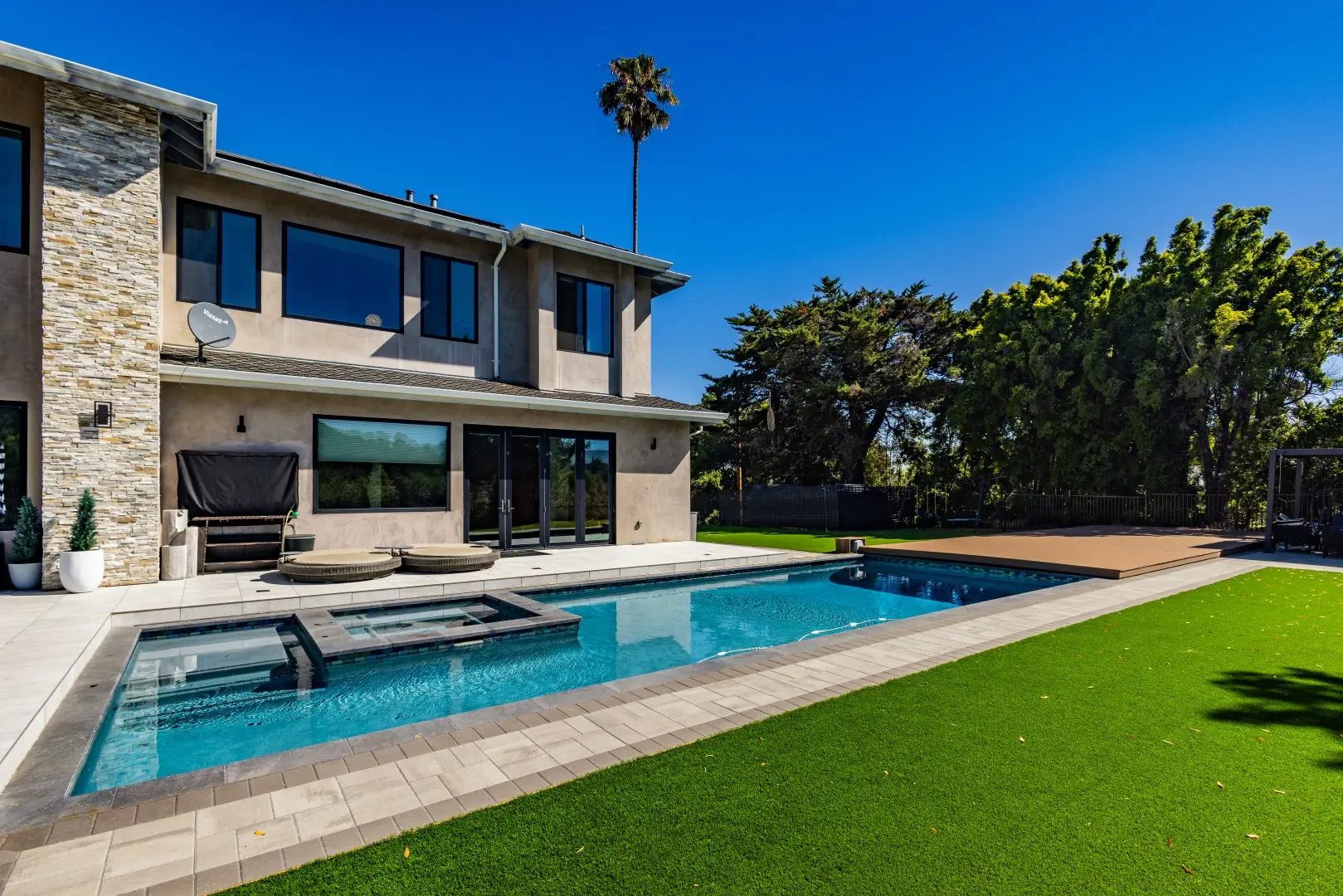 Rectangular pool with an attached spa and a retracted movable deck beside an artificial turf lawn in San Jose, California