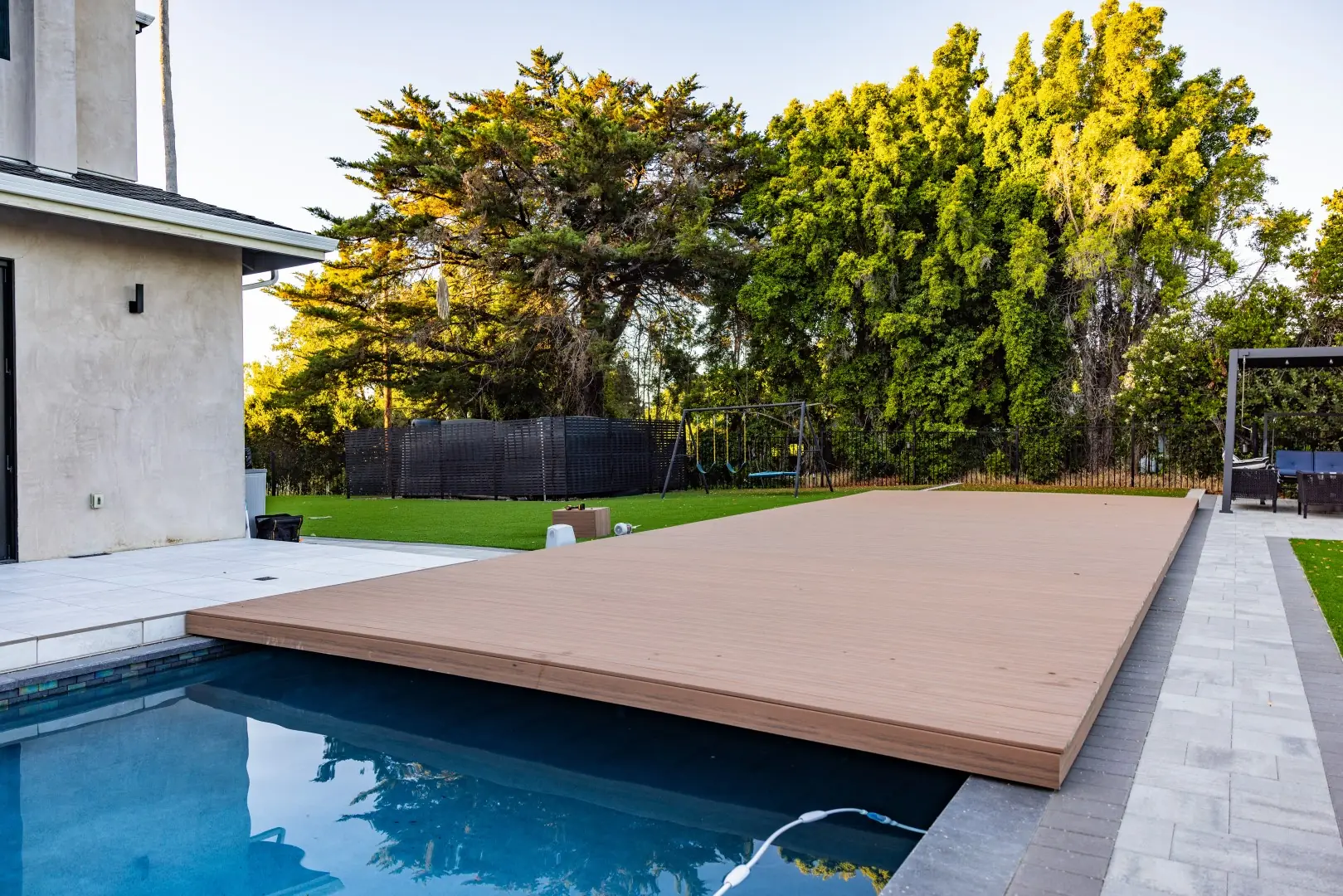 Movable composite deck sliding over a pool to create extra patio space in San Jose, California