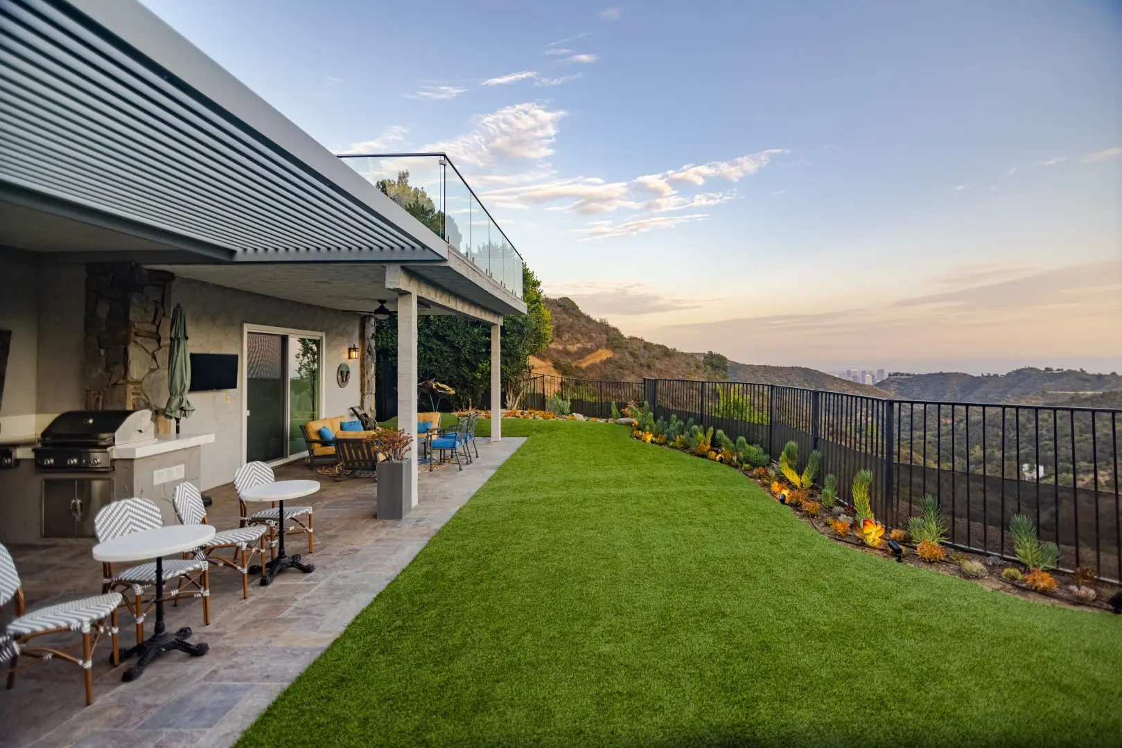 Louvered pergola and bistro seating overlooking an artificial turf lawn and canyon views in Beverly Glen, Los Angeles