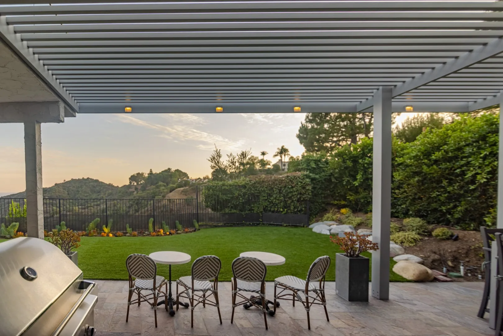 Louvered aluminum patio cover with built-in lights over bistro seating and a hillside lawn in Beverly Glen, Los Angeles