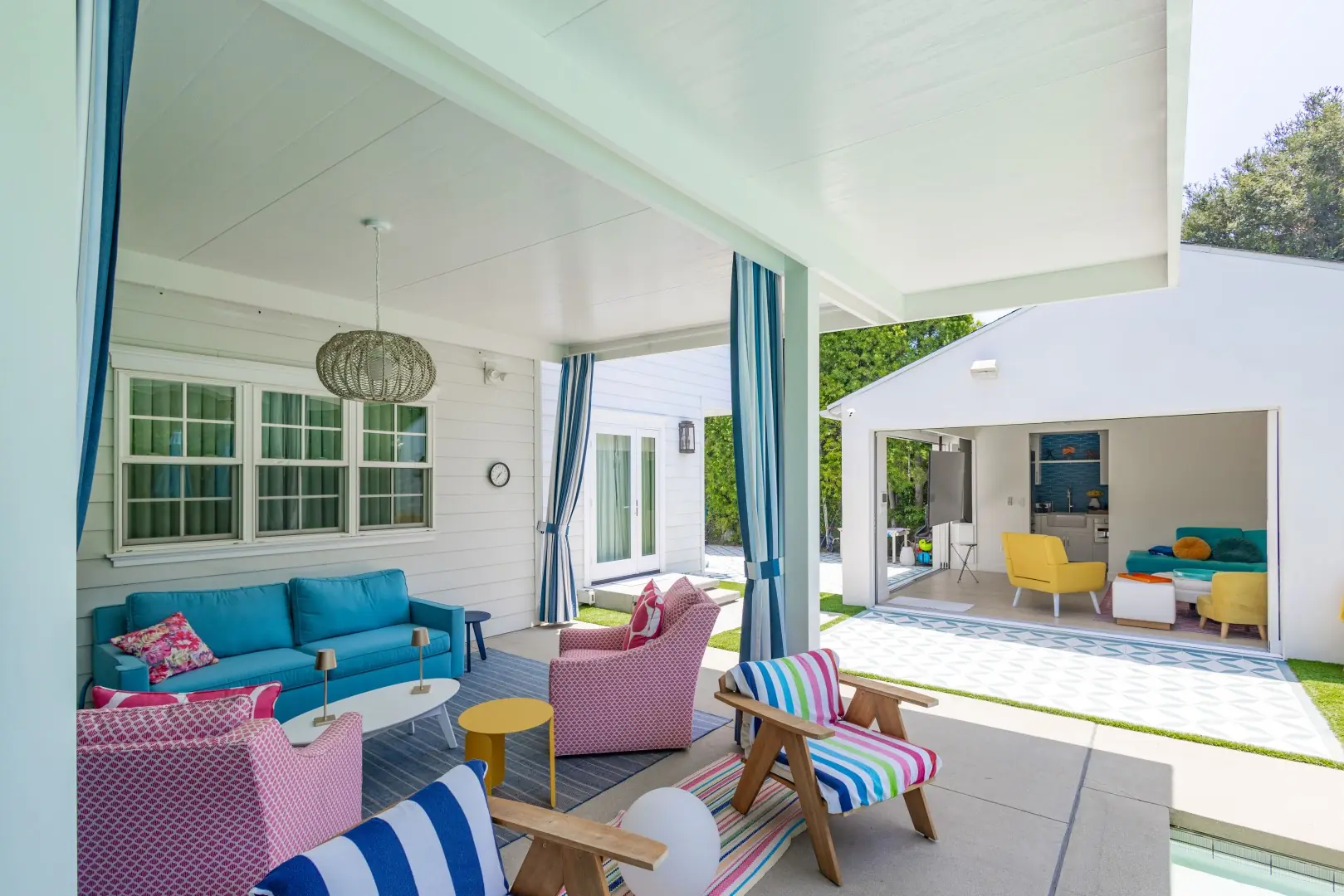 Patio cover lounge with pink and blue seating facing an open pool house in Studio City