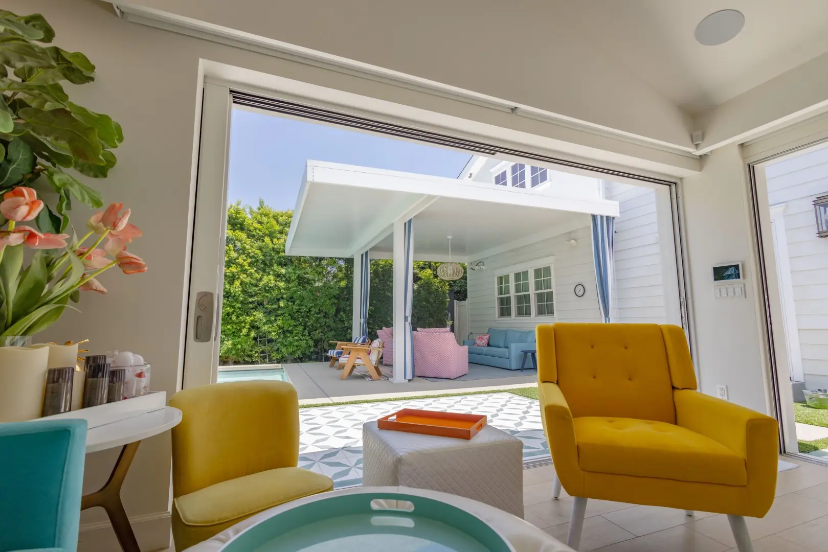 View from a pool house through wide glass doors to a patio cover and lounge in Studio City