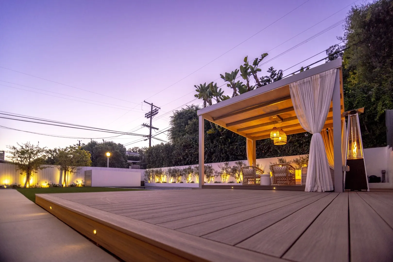 Sheens Project white cabana pergola on the ground-level composite deck with step lights at dusk in Los Angeles