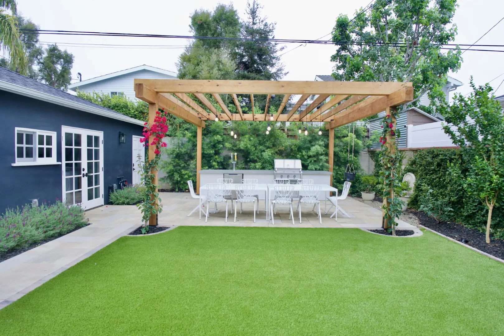 Agnew Project wood pergola with bougainvillea over an outdoor dining area at the end of a turf lawn in Los Angeles